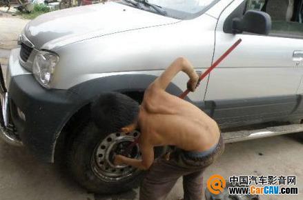 这里是一个私人汽车轮胎修补店。这个光胴胴的小家伙正在给一辆大汽车打黄油。